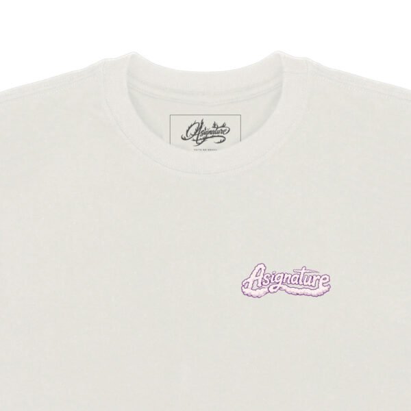 Detalhe frontal da camiseta Asignature GOOD VIBES em off white com logo lilás aplicado no peito e etiqueta interna da marca.